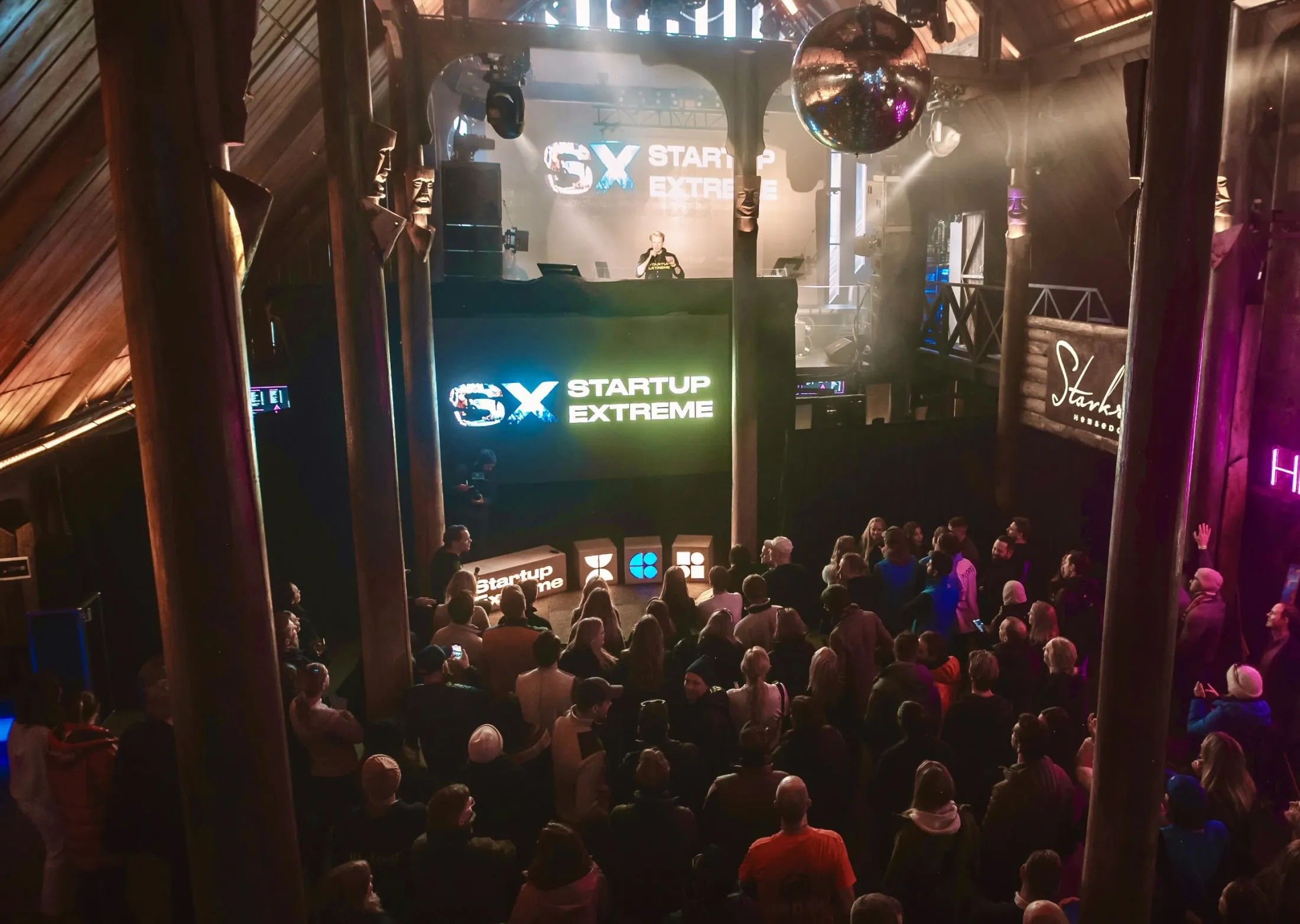The main stage at Stavkroa seen from above: a packed hall, timber pillars and the SX logo on the screen.