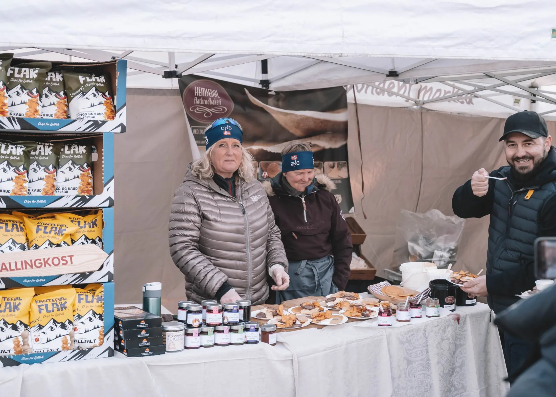Hosts smiling behind a local food stand selling flatbread in the snow.